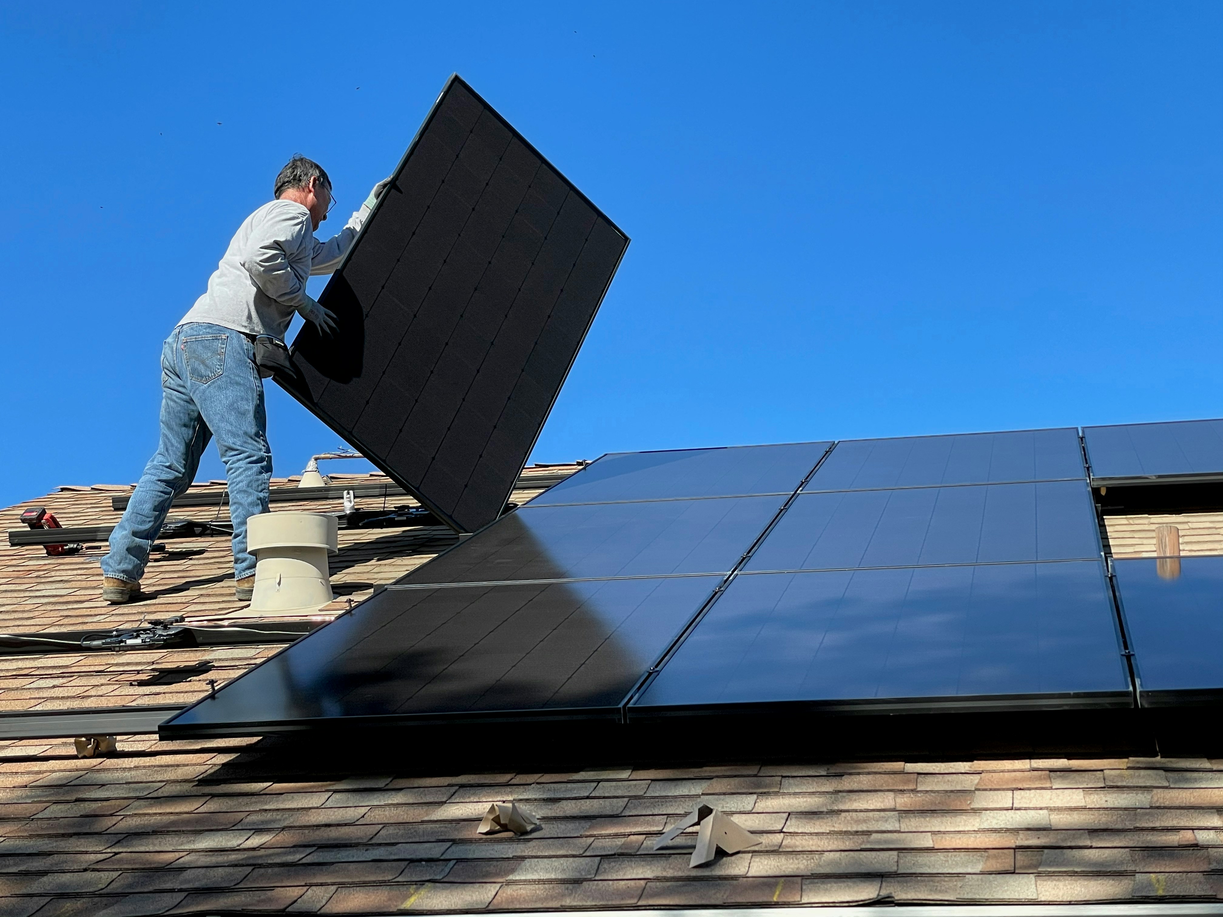 Installer placing solar panel on roof